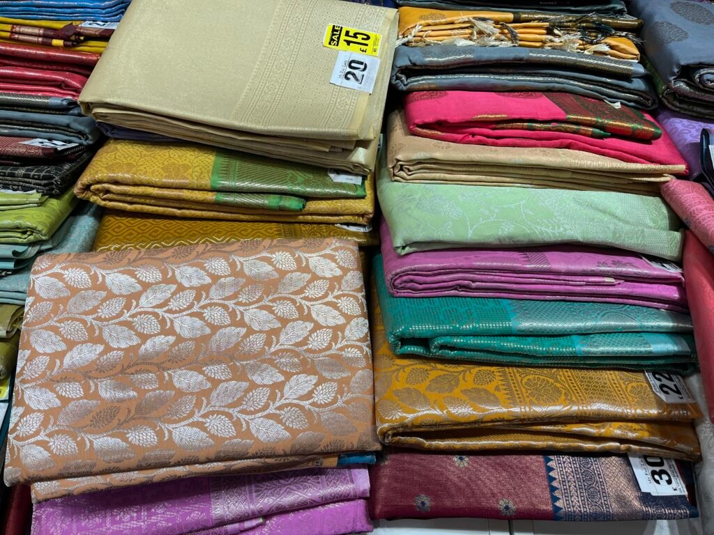 stacks of neatly folded colourful saris in a sari shop on Ealing Road